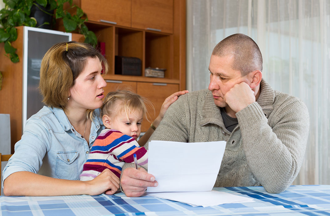 Des parents lisant leurs factures avec leur enfant via Shutterstock