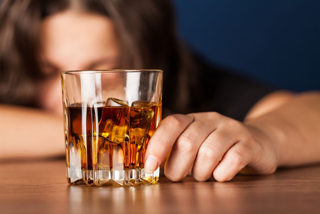 Une jeune femme avec un verre d'alcool à la main via Shutterstock