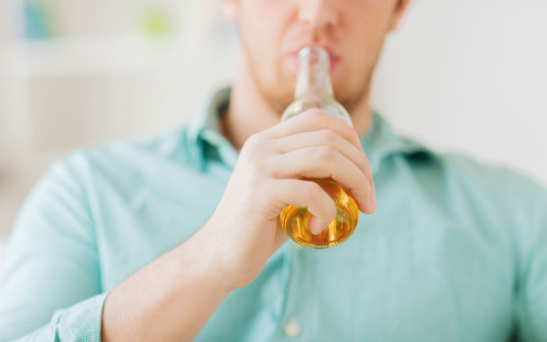 Un jeune homme buvant de la bière via Shutterstock