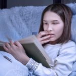 Une jeune fille qui lit un livre dans son lit