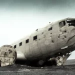 Épave d’un avion écrasé, partiellement désintégré, reposant sur un sol sombre sous un ciel orageux