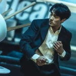 Un homme en costume esquive une chaise lancée lors d'une scène de combat