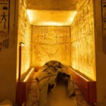 Tombeau égyptien illuminé avec sarcophage ancien et murs décorés de hiéroglyphes et fresques rituelles.