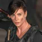 Personnage féminin armé au visage marqué, prêt au combat dans une scène intense de The Old Guard 2