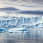 Un gigantesque iceberg en Antarctique flottant au large d’une banquise gelée.