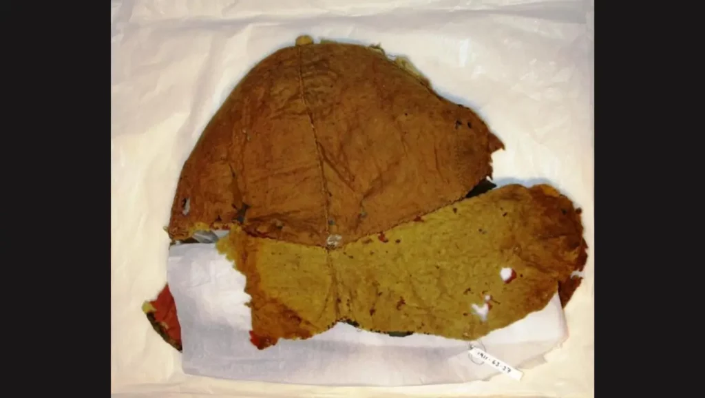 Casque antique en tissu avant restauration, conservé au Bolton Museum en Angleterre.