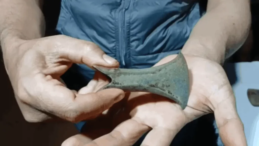 Hache ancienne en métal de 3 000 ans retrouvée en Indonésie, tenue dans les mains d’un habitant.