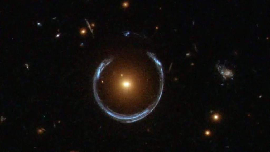 Image d’un anneau d’Einstein capté par Hubble : la lumière d’une galaxie lointaine est déformée en cercle par la gravité d’une galaxie rouge au premier plan.