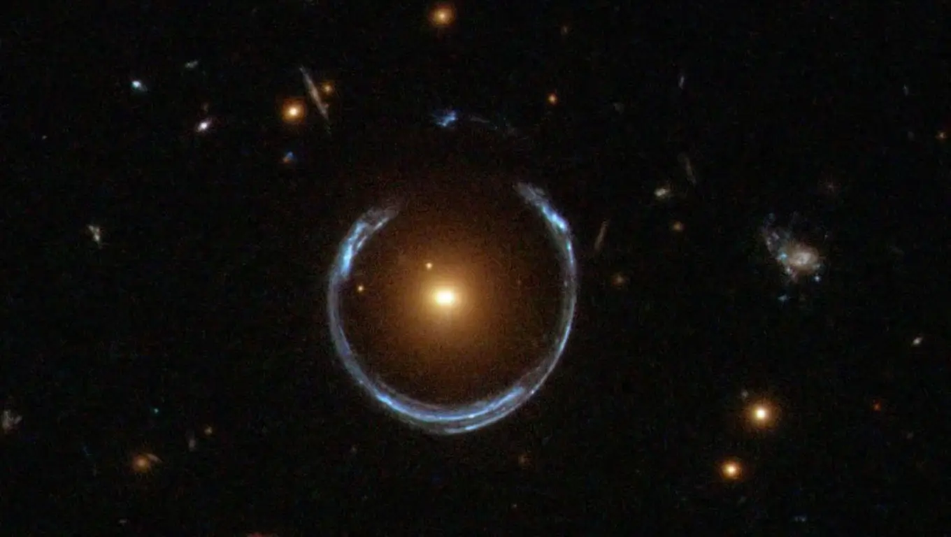Image d’un anneau d’Einstein capté par Hubble : la lumière d’une galaxie lointaine est déformée en cercle par la gravité d’une galaxie rouge au premier plan.