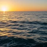Coucher de soleil sur la mer avec vagues, illustrant l’élévation rapide du niveau des océans due au réchauffement climatique