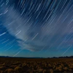 Photo en pose longue d’un ciel étoilé montrant les traînées lumineuses des étoiles.