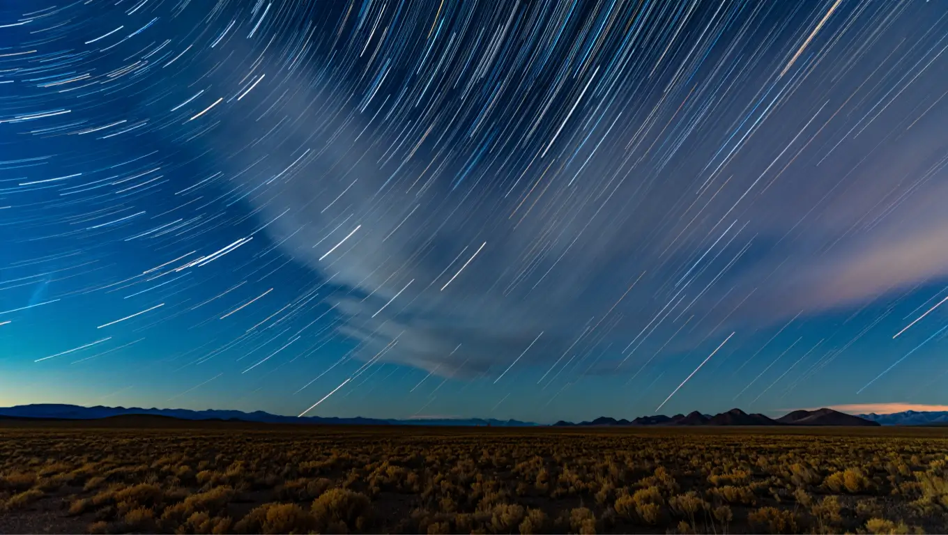 Photo en pose longue d’un ciel étoilé montrant les traînées lumineuses des étoiles.