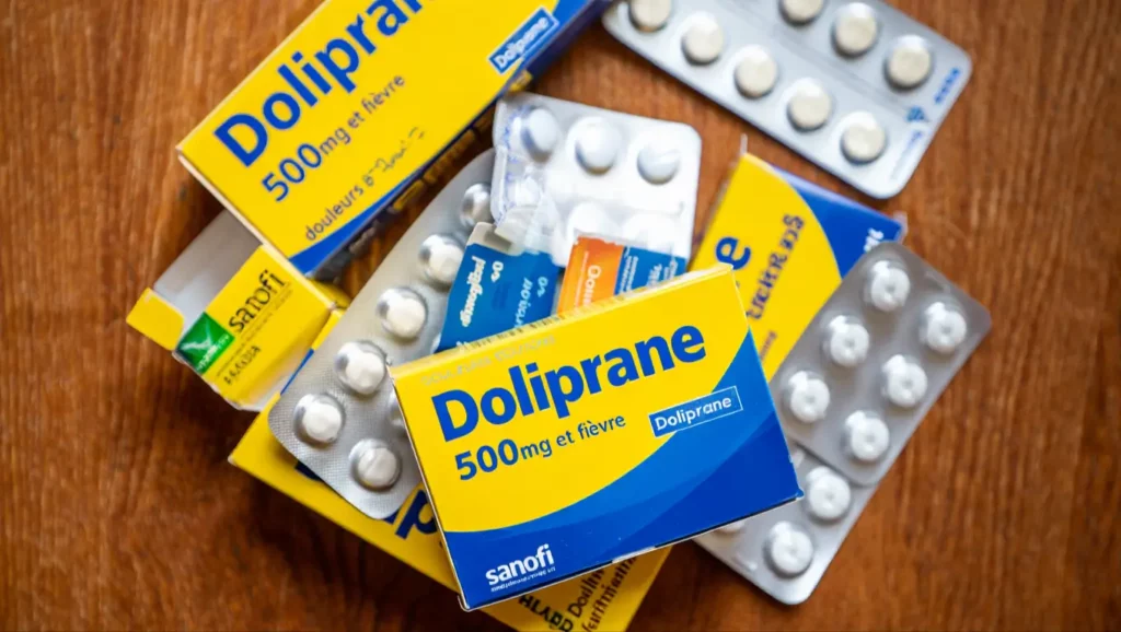 Boîtes et plaquettes de Doliprane 500 mg posées sur une table en bois.