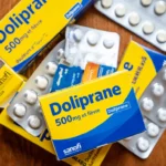 Boîtes et plaquettes de Doliprane 500 mg posées sur une table en bois.