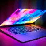 Ordinateur portable Apple MacBook Pro partiellement ouvert avec écran OLED aux couleurs vives.