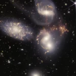 Image capturée par le télescope spatial James Webb montrant un amas de galaxies en interaction, révélant un monstre galactique aux confins de l’univers observable.