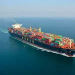 Vue aérienne d’un cargo chinois transportant des centaines de conteneurs colorés en pleine mer, symbole des nouvelles avancées technologiques du transport maritime.