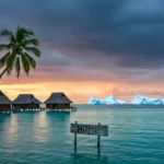 Pays tropical menacé par la montée des eaux, avec des maisons sur pilotis, des palmiers et des icebergs anormalement proches à l’horizon au coucher du soleil.