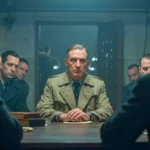 Homme en imperméable assis face à plusieurs officiers dans une salle sombre, scène d’interrogatoire inspirée de L’Armée des Ombres.