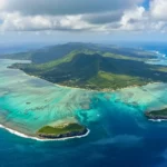 Vue aérienne d’une île de Guadeloupe entourée de lagons turquoise, récifs coralliens et reliefs verdoyants
