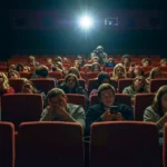 Spectateurs frustrés dans une salle de cinéma, regardant leur téléphone après la projection d’Avatar 3 sans teaser Marvel
