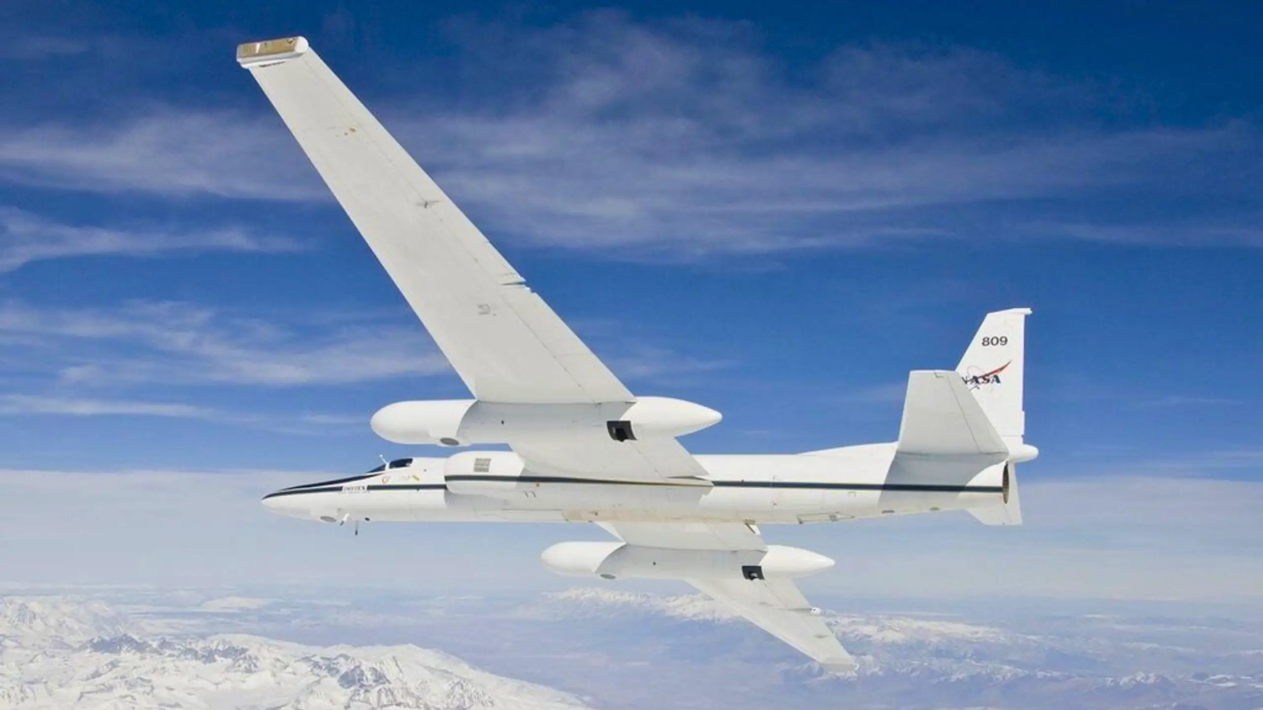 Avion de recherche NASA survolant des canyons rouges désertiques avec des tracés géométriques au sol, sous un ciel bleu clair.