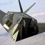 Avion furtif F-117 Nighthawk en vol au-dessus d’un paysage désertique, illustrant la technologie de furtivité radar.