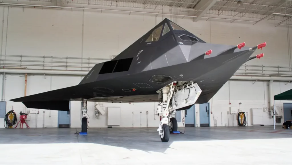 Avion furtif F-117 Nighthawk stationné dans un hangar, montrant sa forme angulaire conçue pour échapper aux radars.