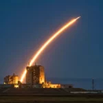 Fusée laissant une traînée lumineuse lors de son lancement depuis une base spatiale au crépuscule.