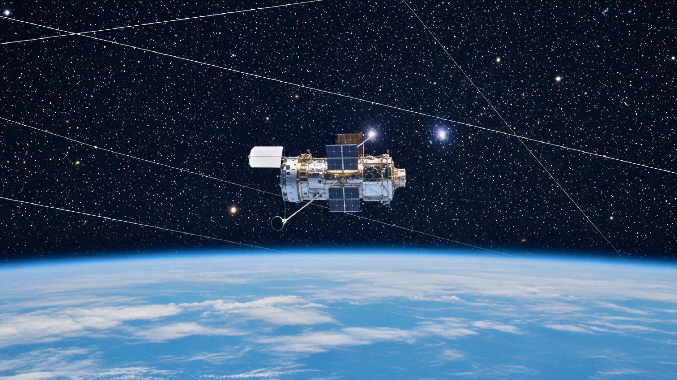 Le télescope spatial Hubble en orbite au-dessus de la Terre, avec plusieurs traînées lumineuses de satellites traversant le ciel étoilé.