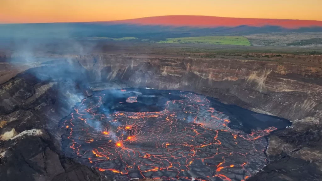 Vue aérienne d’un lac de lave actif dans le cratère du volcan Kilauea, avec des fissures incandescentes et de la fumée s’élevant dans l’air.