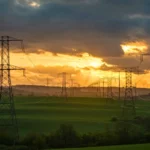 Lignes à haute tension traversant une campagne française au coucher du soleil, symbole du record d’exportation électrique et du surplus d’énergie en France.