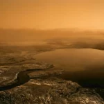 Paysage de Titan avec des étendues de liquides et des formations géologiques sous une atmosphère orangée et brumeuse.