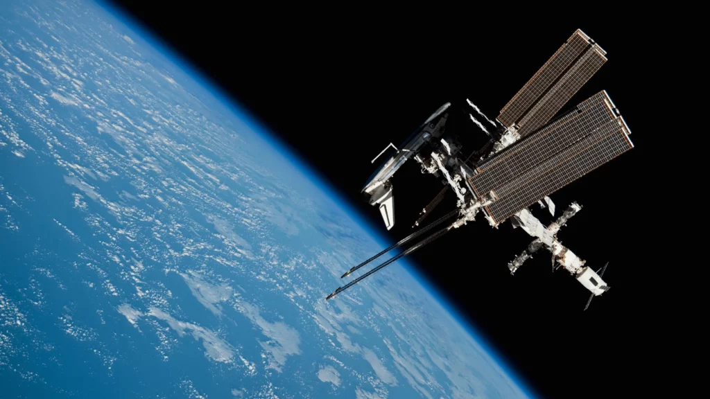La Station spatiale internationale en orbite, vue depuis l’espace avec la Terre en arrière-plan bleu et nuageux.
