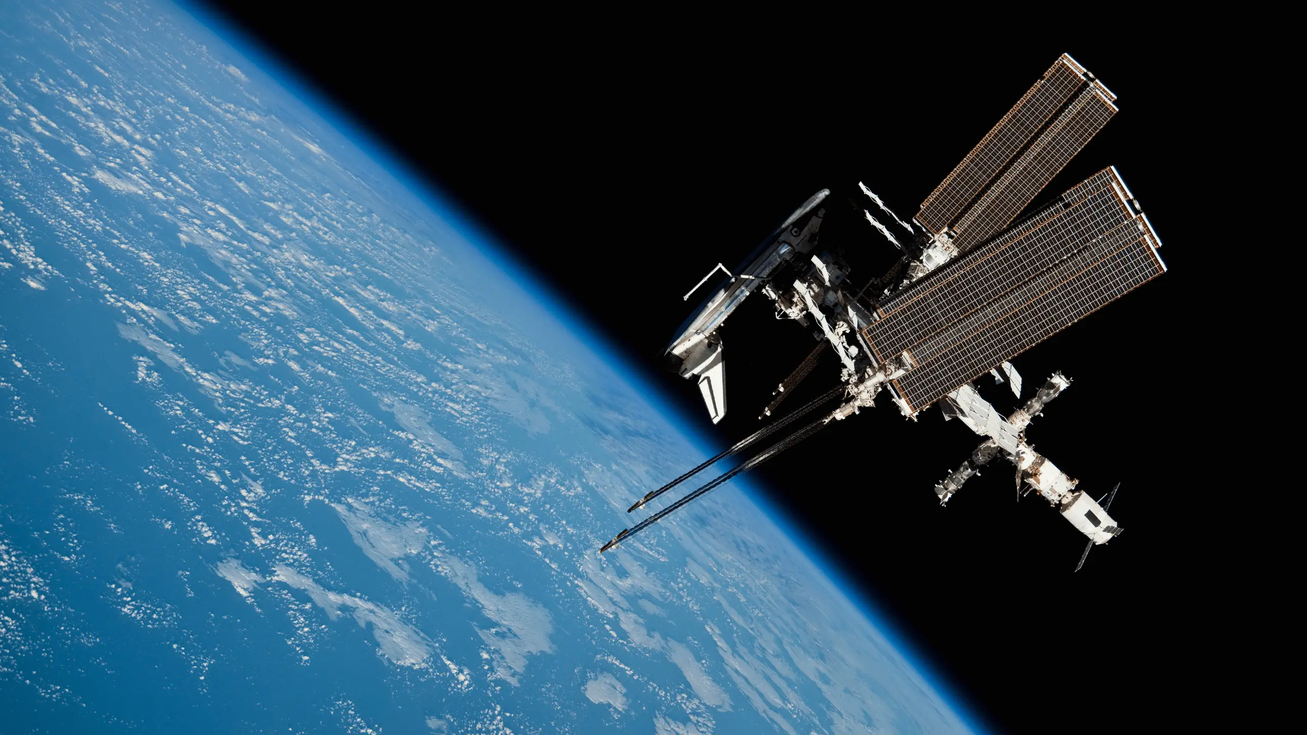 La Station spatiale internationale en orbite, vue depuis l’espace avec la Terre en arrière-plan bleu et nuageux.