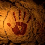 Peinture rupestre main négative ocre rouge sur paroi calcaire grotte