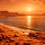 Une vaste mer fossile sur Mars au coucher du soleil, bordée de rochers rouges et de falaises abruptes sous un ciel orangé.