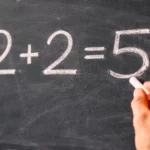 Écriture à la craie de l’équation 2 + 2 = 5 sur un tableau noir illustrant un paradoxe mathématique