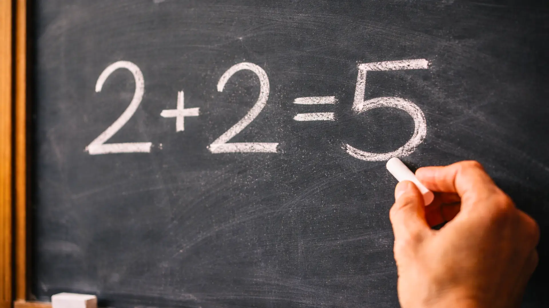 Écriture à la craie de l’équation 2 + 2 = 5 sur un tableau noir illustrant un paradoxe mathématique