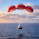 Capsule spatiale Crew Dragon descendant sous parachutes au-dessus de l’océan lors d’un retour anticipé depuis l’ISS.