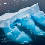Iceberg A-23A en cours de fonte dans l’océan Austral, révélant des arches de glace bleutée formées par le réchauffement des eaux.