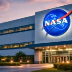 Façade moderne d’un bâtiment de la NASA au crépuscule, avec le logo officiel illuminé sur le mur principal.