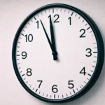 Horloge murale minimaliste indiquant une heure très proche de minuit, photographiée dans un environnement institutionnel sobre.