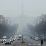 Paris sous un nuage de pollution avec circulation dense et visibilité réduite autour de l’Arc de Triomphe