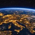 Vue nocturne de l’Europe depuis l’orbite terrestre, montrant les villes illuminées en France, Italie et Allemagne avec la courbure de la Terre visible.