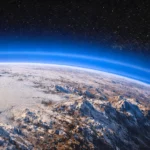 Pluton vue depuis l’espace avec une fine brume bleutée s’élevant au-dessus de sa surface glacée et de ses plaines d’azote gelé.