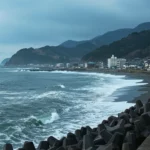 Côte de Sanriku au Japon avec vagues agitées après un séisme, digue et habitations en arrière-plan