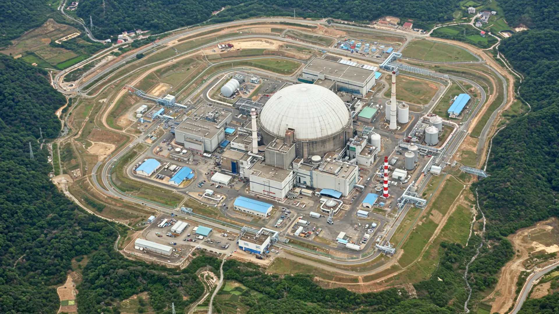 Vue aérienne d’un complexe nucléaire avec un grand dôme et des installations industrielles dans une zone rurale du Sichuan en Chine