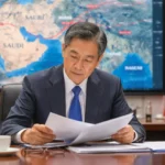 Responsable chinois lisant des documents devant une carte du Moyen-Orient avec drapeaux chinois et iranien