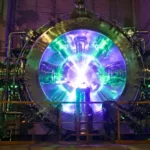 Une immense chambre à vide en acier émettant une lumière intense verte et violette, avec un cœur de plasma brillant au centre d’une installation industrielle.
